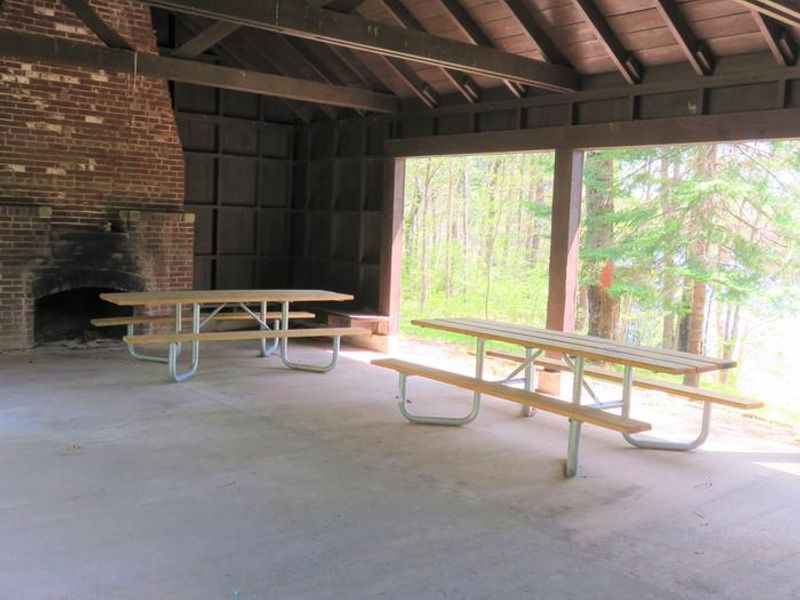 View of some picnic tables and one fireplace inside the Picnic Point Shelter