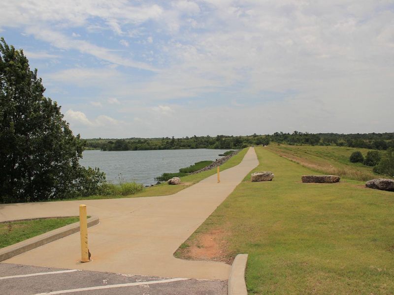 A view of the dam area and trail on Veteran's Lake under a blue sky