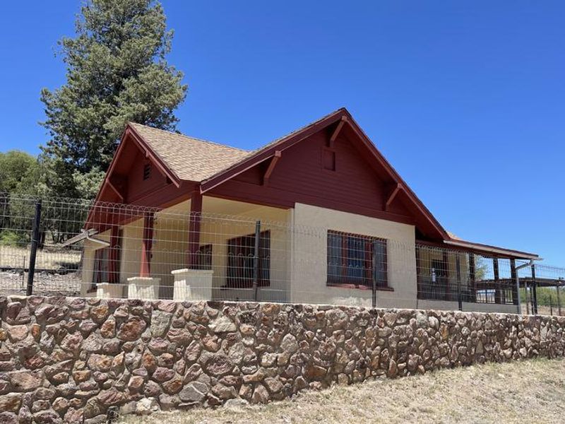 Canelo Ranger Residence, view of house from the driveway. Lawn edge lined by a historic CCC stone wall and safety fence.