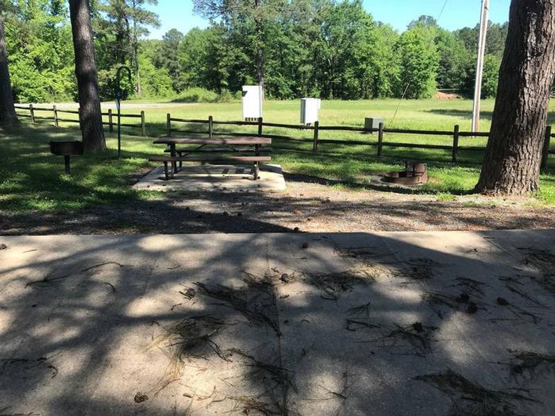 Shaded Class A Campsite #6. RV pad, water, and 20/30/50 AMP electric hook-ups as well as basic campsite amenities including a picnic table, lantern post, fire ring, trash can and grill.