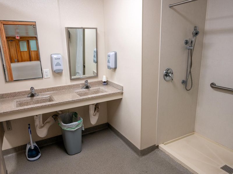 Each dorm has two bathrooms; one bathroom is located in each wing of the building. Each bathroom contains one shower with a folding shower chair, two sinks, and two mirrors. Not included in the photo are two toilet stalls. 