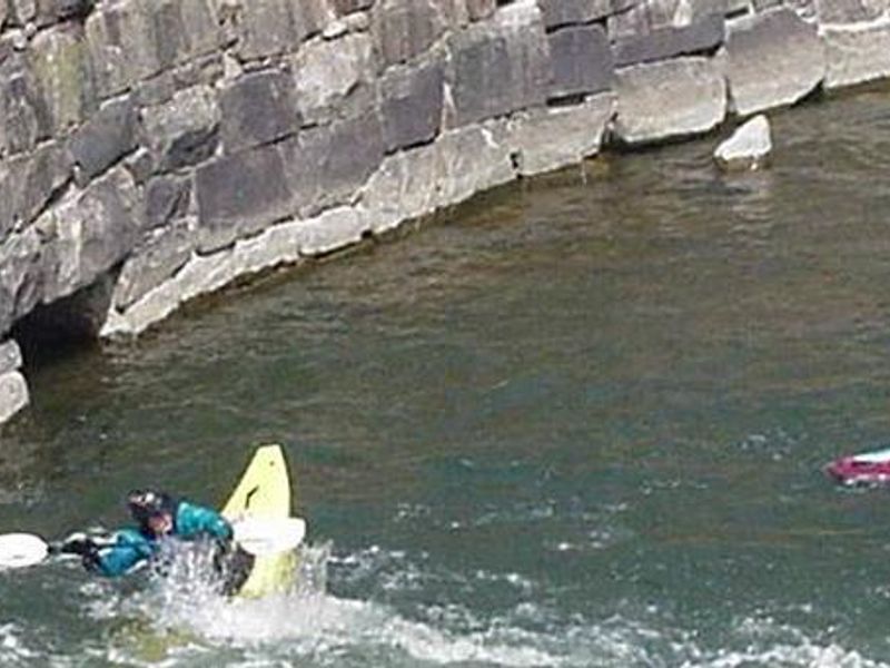 Kayakers Playing in River by Old Dam