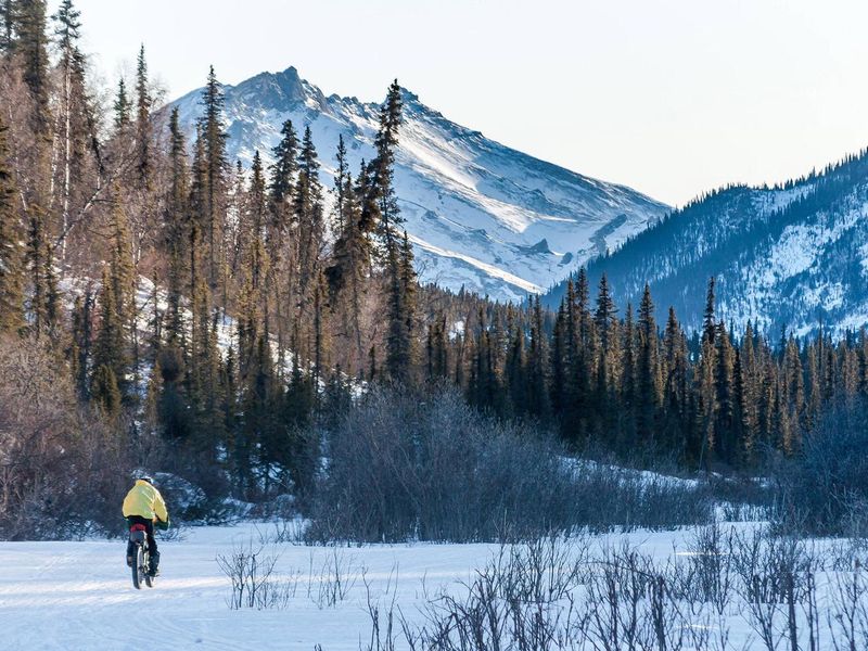 A bicyclist pedals along frozen Fossil Creek near Windy Gap Cabin.