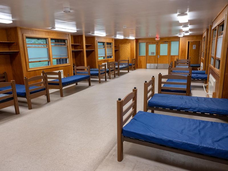 Each dormitory is heated and  accommodates 30 overnight guests.  There are 15 single beds on each of the 2 connected wings.  Each wing has a separate room with 1 single bed.  There are a set of bathrooms for each wing and a supply closet with cleaning equipment.