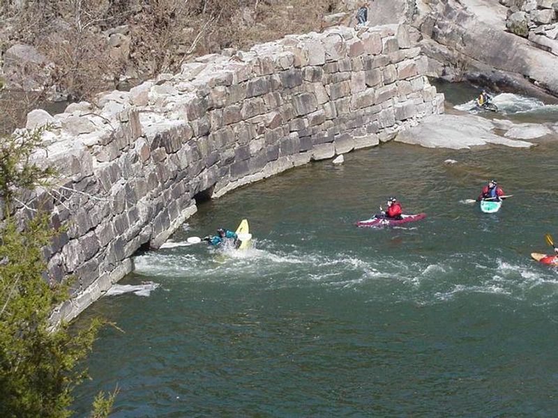 Kayakers Playing in River by Old Dam