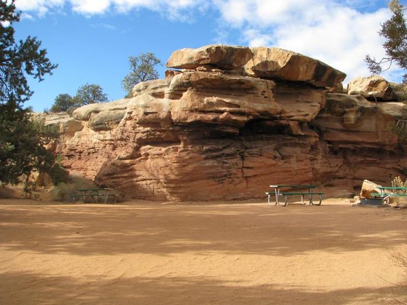 Sandy camping area next to picnic table.