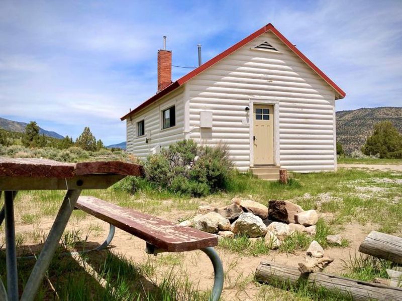 Orange Olsen Cabin's small outdoor seating area with a wooden picnic table and a stone fire pit.