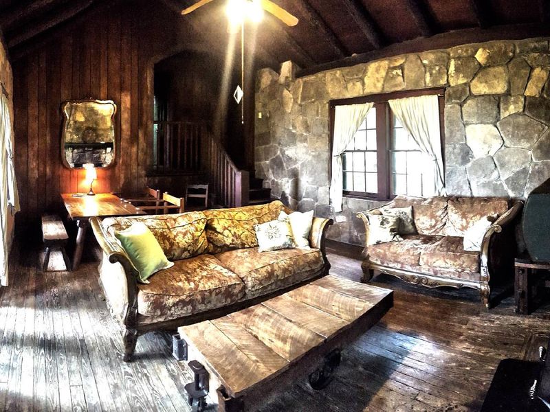 Cabin B's living room is beautifully furnished with antique and new furnishings, features a large rock fireplace and walls, comfortable and unique!