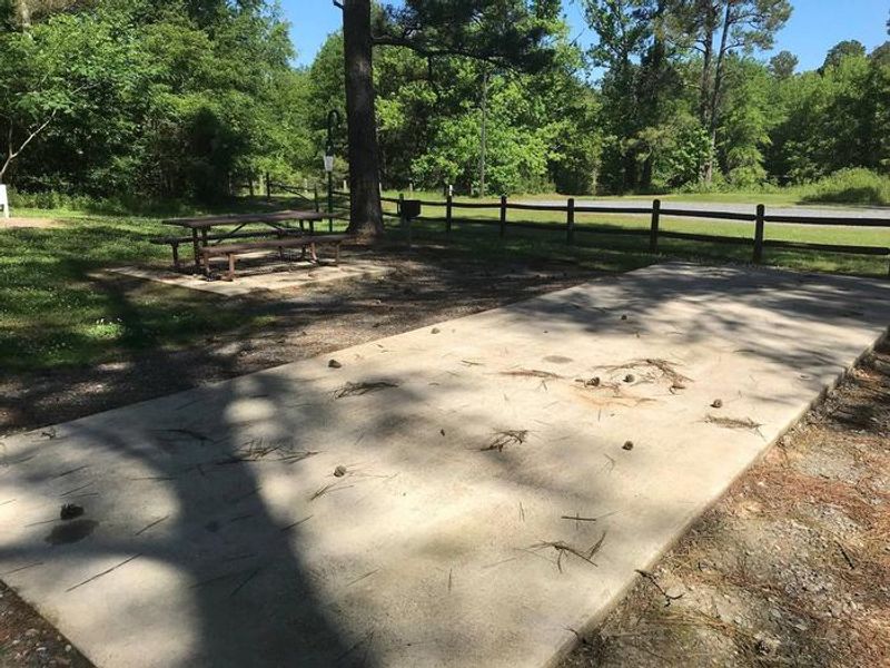 Shaded Class A Campsite #7. RV pad, water, and 20/30/50 AMP electric hook-ups as well as basic campsite amenities including a picnic table, lantern post, fire ring, trash can and grill.