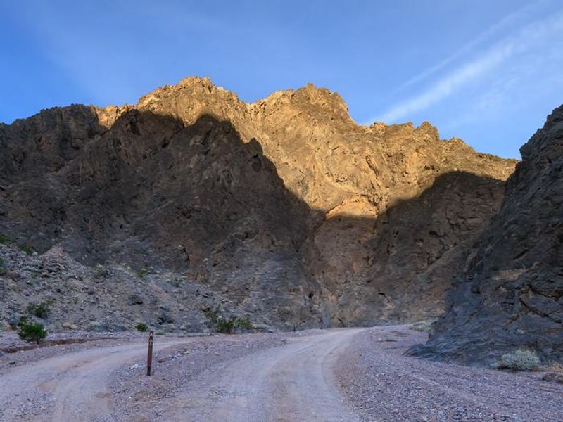 Gravel dirt road with a parallel roadside campsite. 