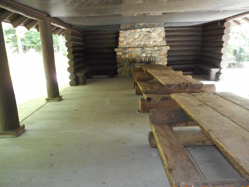 Lake Ottawa Campground picnic shelter with two stone fireplaces and original log picnic tables.
