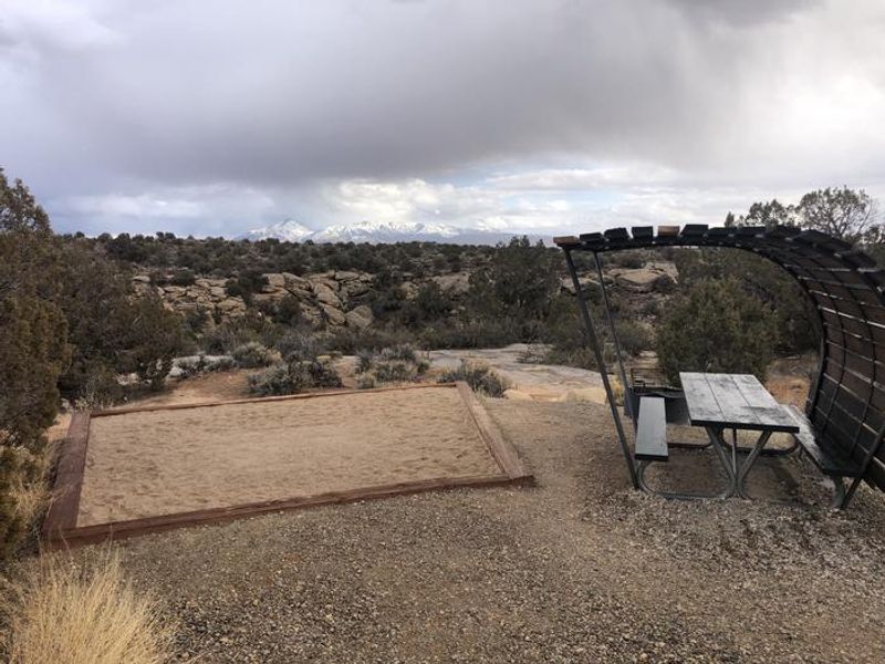 Tent campsites have picnic tables with shade structures, along with a tent pad. 