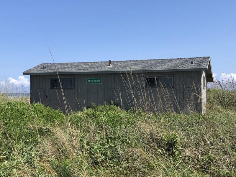 View of the exterior of the Great Island Cabin Camp Bath House from the camp road looking towards the ocean beach.