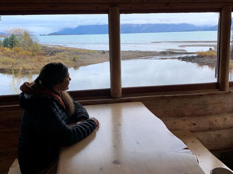 A lodger views Lake Clark through a window inside Priest Rock cabin