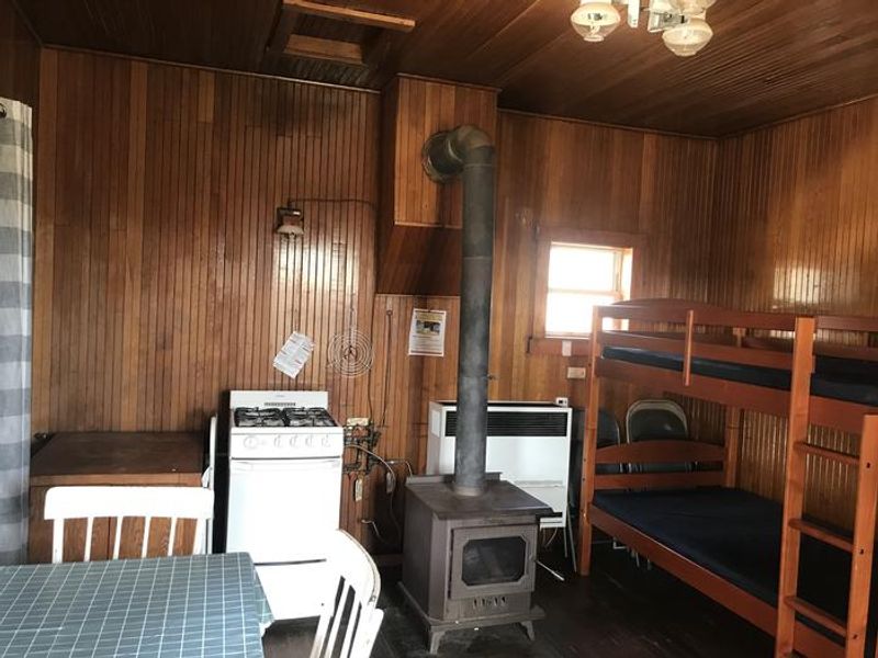The main room serves as the kitchen and sleeping room with a wood stove, propane appliances and two bunk beds with mattresses. 