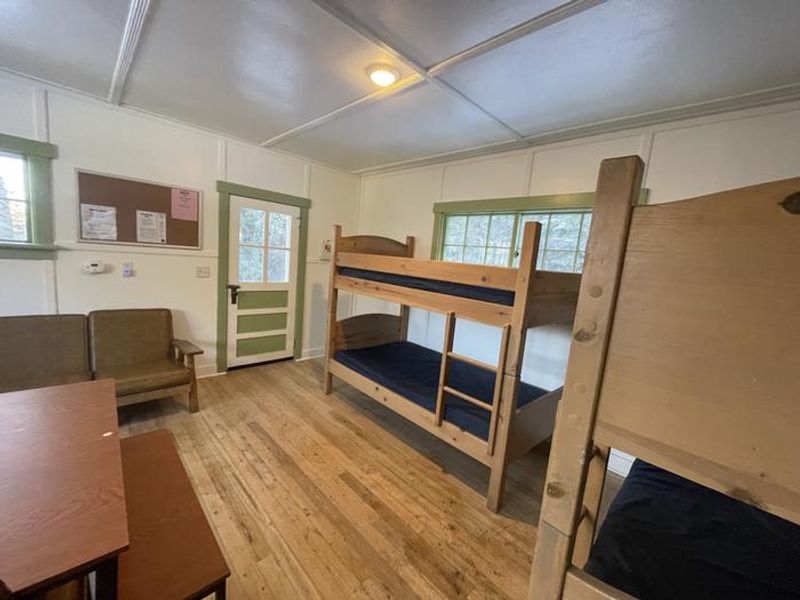 The living room has a wooden couch with cushions and two bunk beds.