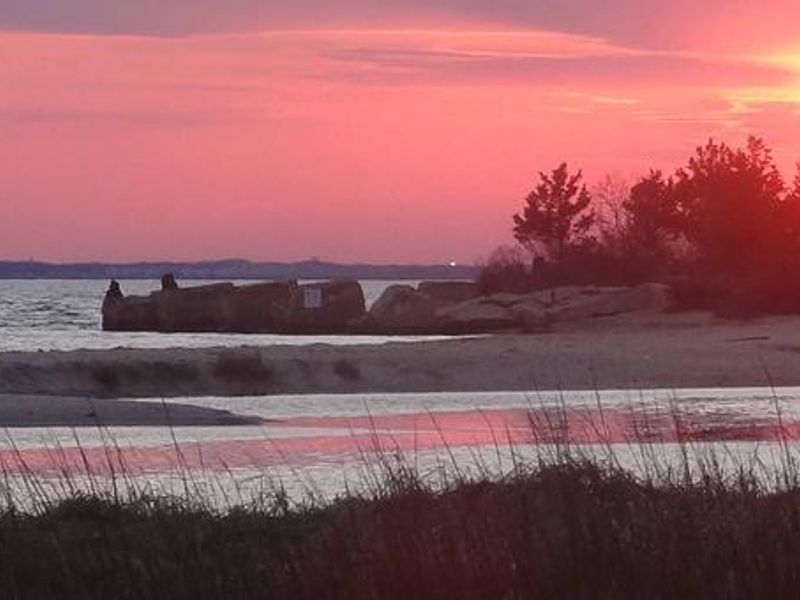 2 Park visitors walking on the beach at Horseshoe Cove while the sun is setting
