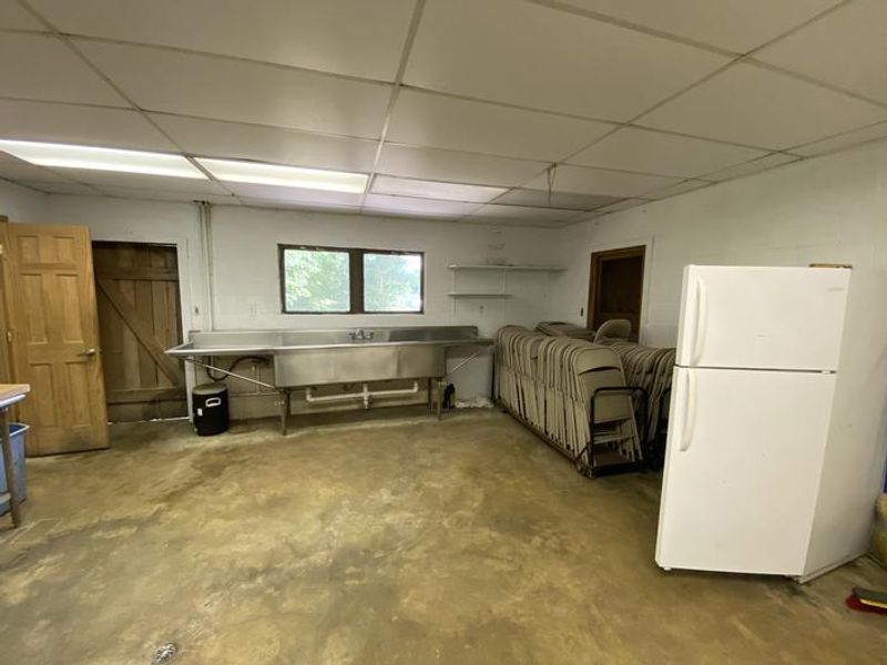 A refrigerator, commercial sink, and chairs are located inside the pavilion.