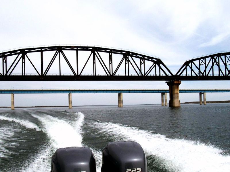 The wake behind a boat as it passes under the Highway 90 Bridge
