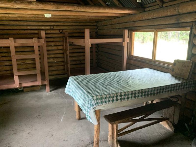 Inside a rusting cabin is two bunkbeds and a dinning table and chairs