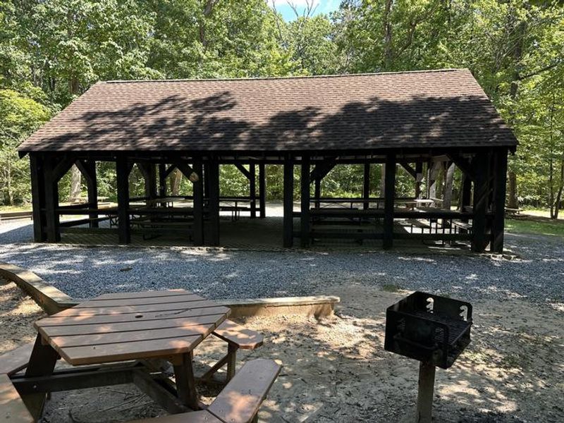 Scattered around the picnic pavilion are more picnic tables and standing charcoal grills