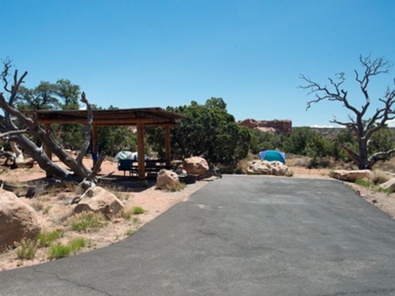 Campsites have shade structures, picnic tables, and paved parking areas.