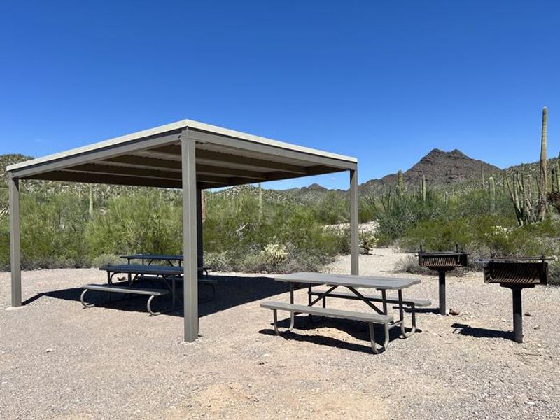 A photo of a group site at TWIN PEAKS CAMPGROUND with a shade Ramada, picnic table, a grill