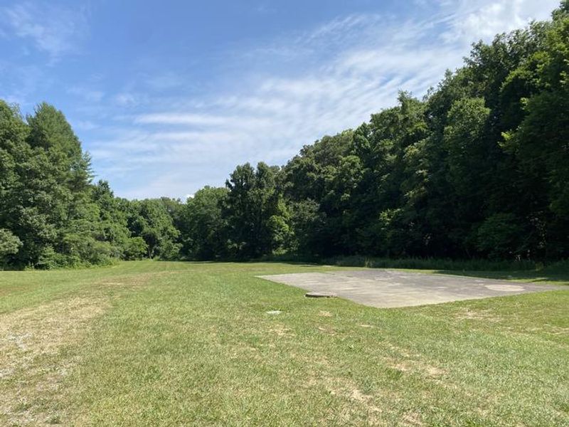 Two large fields with a helipad are located next to the buildings.