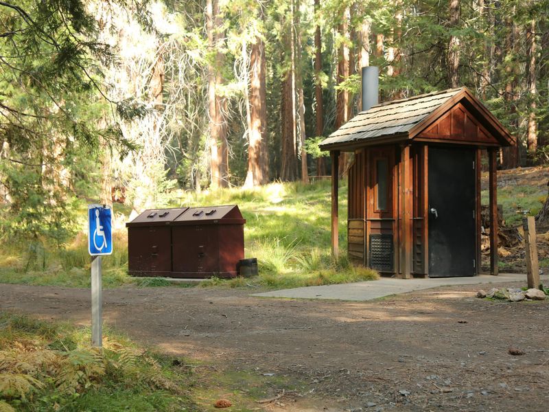 The ground around the restroom is level and firm-packed.
