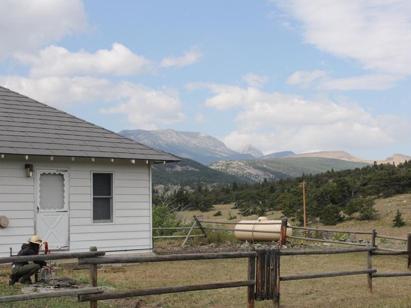 Front door to small white cabin with mountains in background