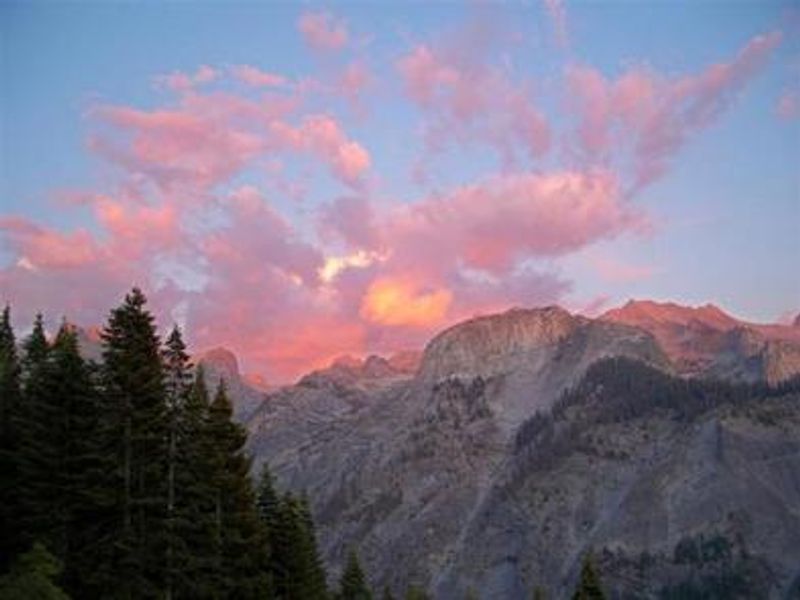 Mountains with conifers and clouds at sunset.