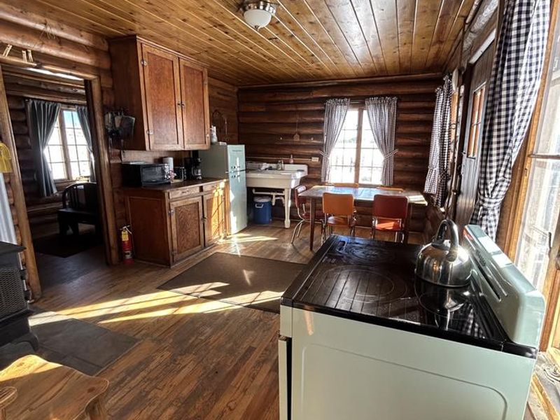 The kitchen includes a refrigerator and electric cooking stove, tables and chairs, and a minimum amount of cabinetry. 