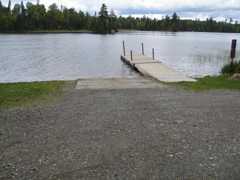 Boatlanding with dock and concrete boat ramp.  Area is located adjacent to small parking area.