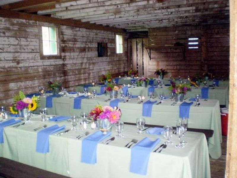 Sample inside setup for AA Barn with linens on table, glasses.  Also shows rough interior walls and small windows.