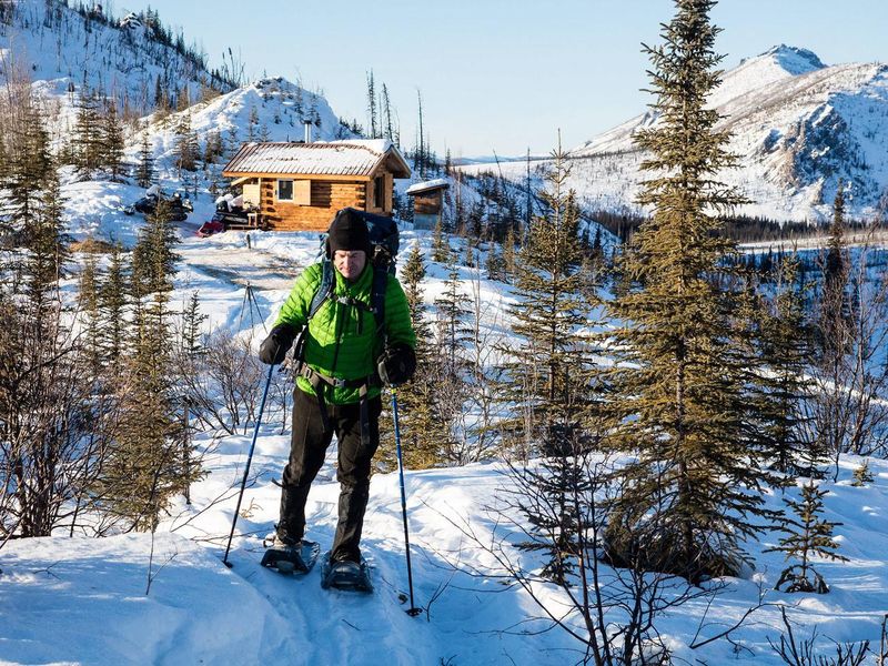 A snowshoer departs from Caribou Bluff Cabin in the White Mountains National Recreation Area.