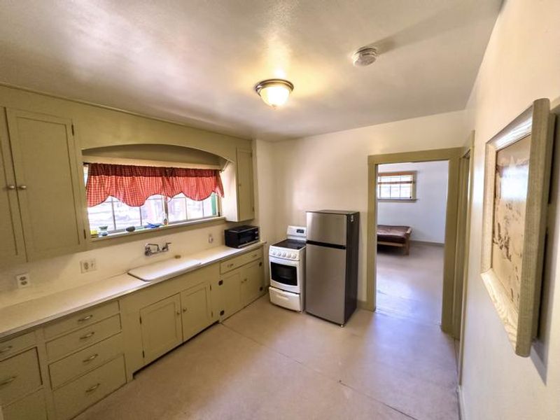 Kitchen is equipped with a refrigerator, stove/oven, microwave, sink, and fold down table. 