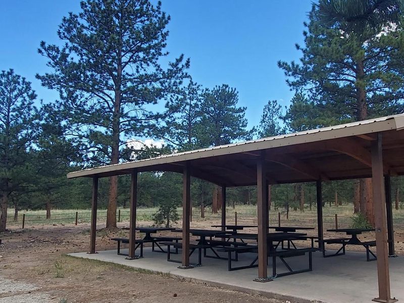 The pavilion provides several moveable tables with a large firepit and a double-vault toilet
