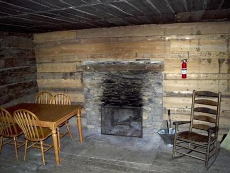 Fireplace, table and chairs, and rocking chair inside cabin