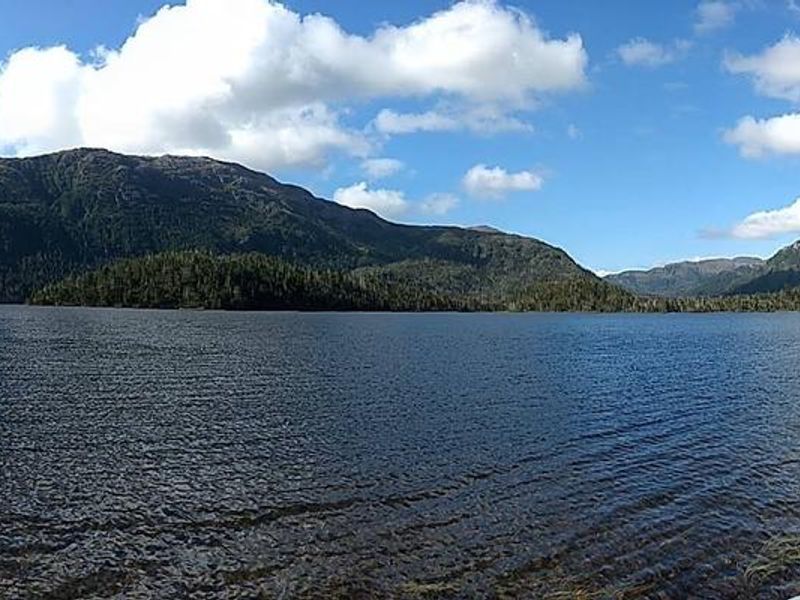 End of trail near lake outlet looking toward toward cabin across lake.  For those hiking in, boat may be here or at cabin.  Hike-in cabin users should bring a pack-raft or be prepared to make a difficult off-trail hike around the lake to the cabin.