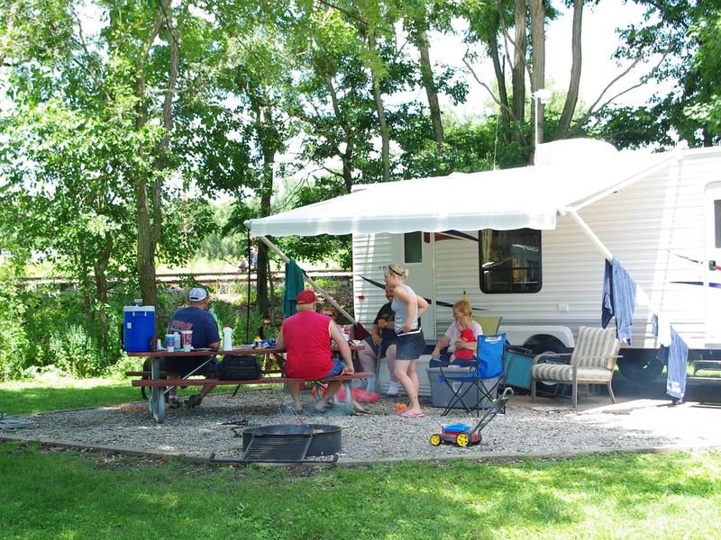 Campers visiting at campsite around picnic table.