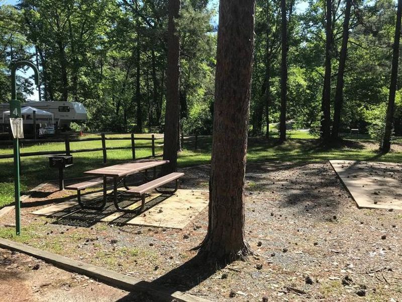 Shaded Class A Campsite #4. RV pad, water, and 20/30/50 AMP electric hook-ups as well as basic campsite amenities including a picnic table, lantern post, fire ring, trash can and grill.