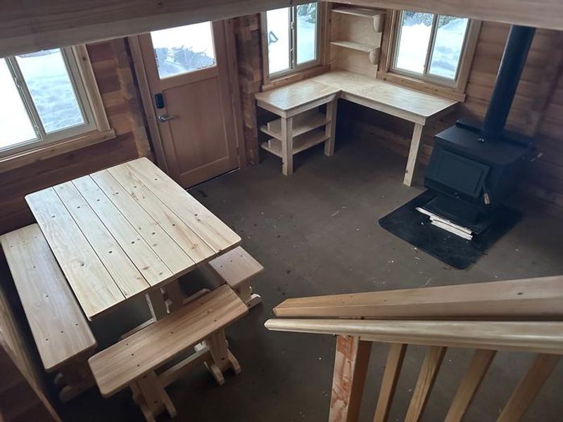 View of the downstairs area from the interior stairs.  Showing the kitchen area, wood stove, and table. 
