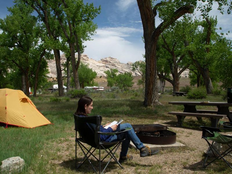 Camper in relaxing in camp chair in campsite. 