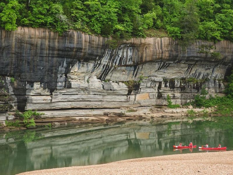 Two red canoes paddle by Painted Bluff on the Buffalo River. 