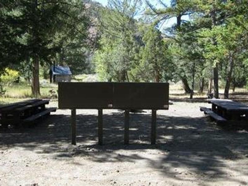 Sign with picnic tables and restroom in the background