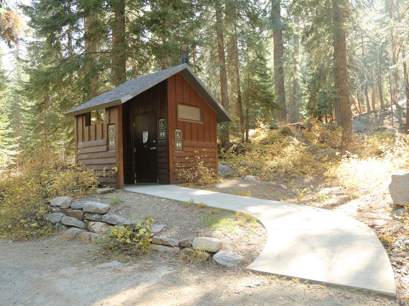 This vault toilet has a paved, wide path to its entrance.