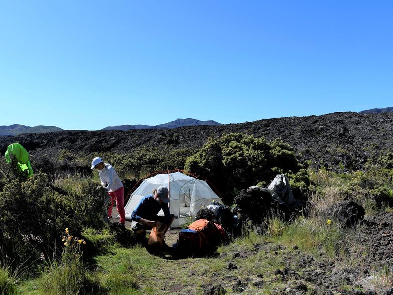 Two backpackers pack up their camp at Hōlua tent site 1.