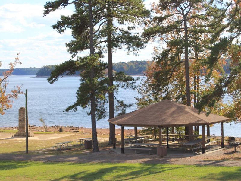 This is a picture of the Old Picnic Area Shetler. This is a picture over looking the area from the nearby road. There are picnic tables under the shelter. This shelter has electricity and a water spigot. There are trash cans located throughout the park. 
