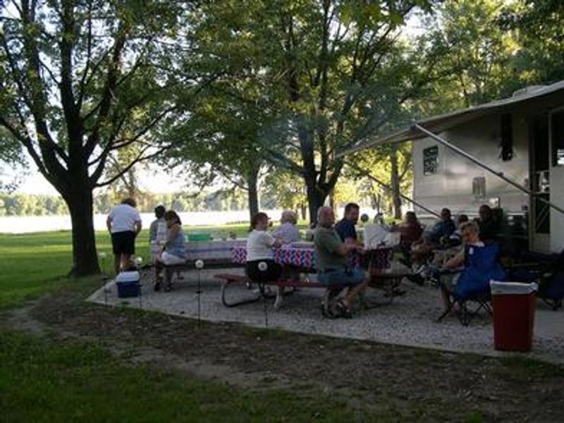 Large Group of people at campsite picnic tables.