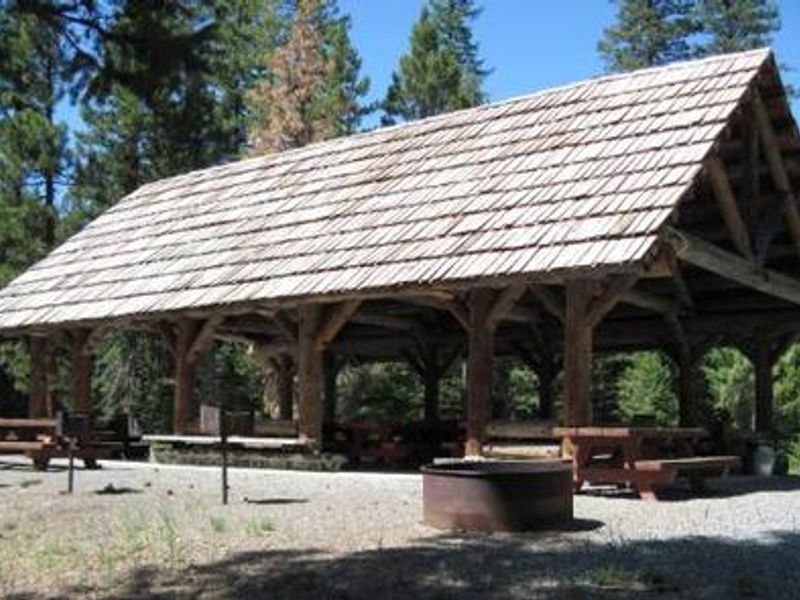 Fire ring and picnic tables in front of large picnic shelter